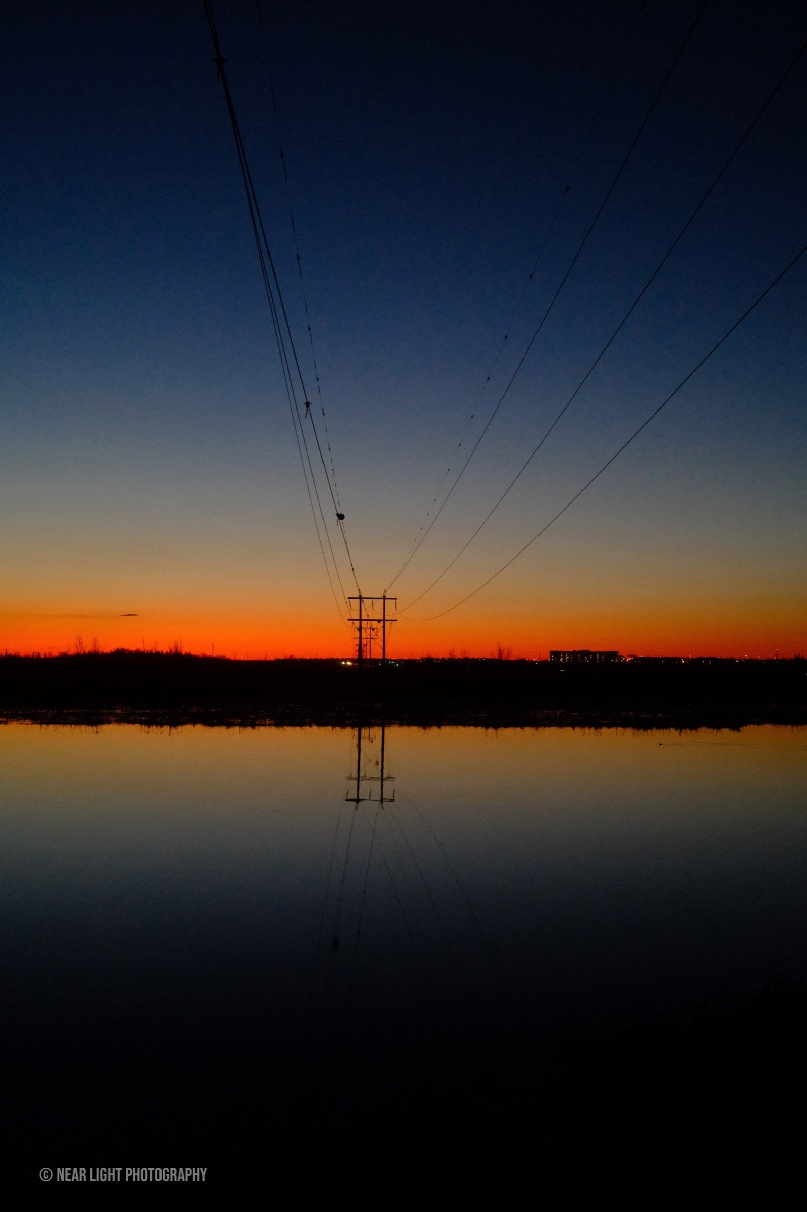 Power lines reflected in water at dusk