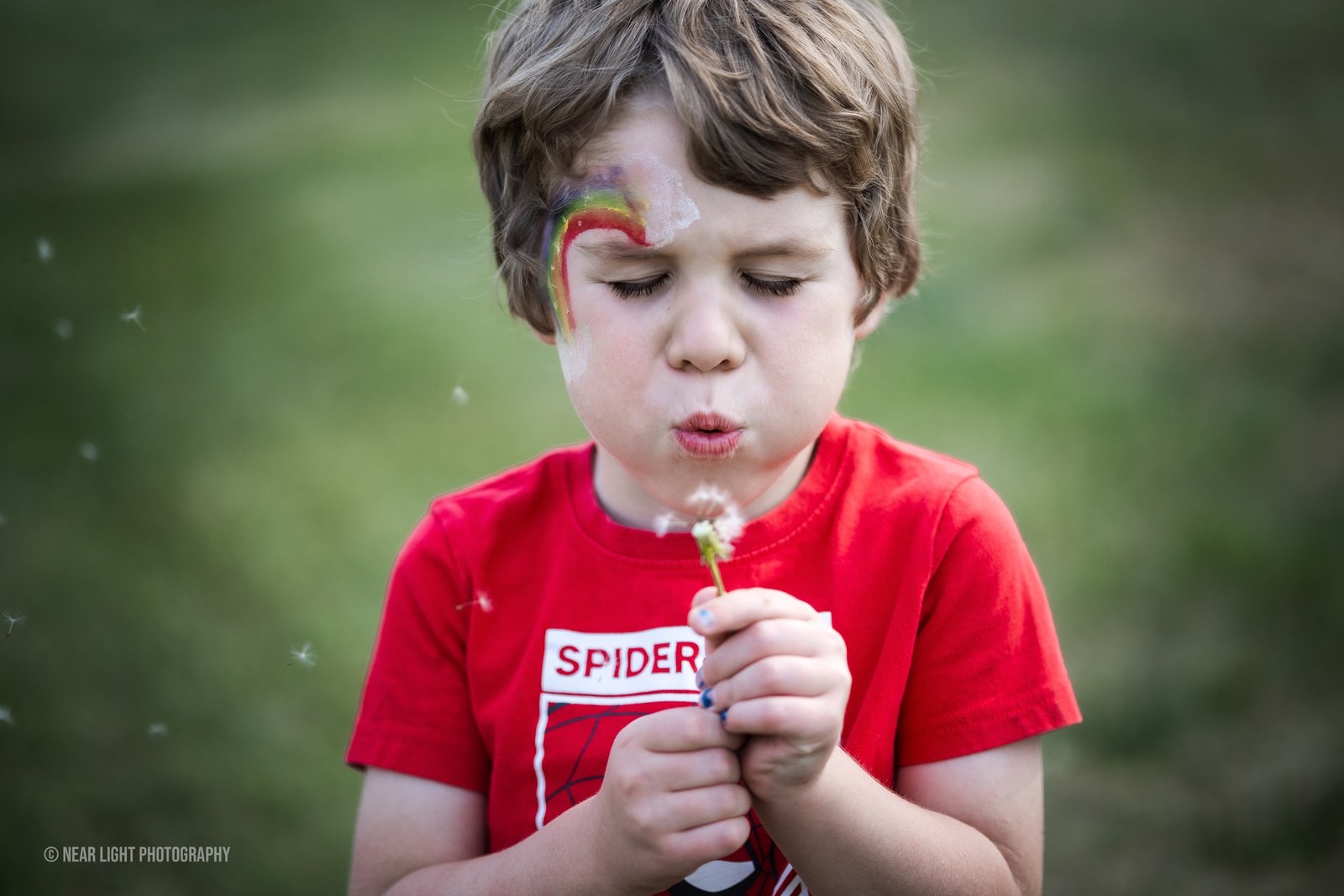 Child blowing dandelion seeds outdoors
